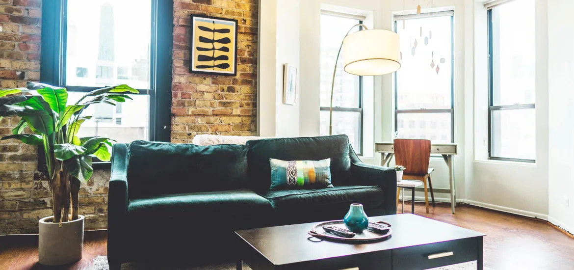 Helles Wohnzimmer einer modernen Stadtwohnung mit Sofa, Pflanze und großen Fenstern – Symbolbild für BGH erleichtert Eigenbedarfskündigung