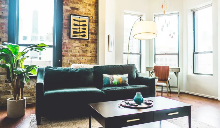 Helles Wohnzimmer einer modernen Stadtwohnung mit Sofa, Pflanze und großen Fenstern – Symbolbild für BGH erleichtert Eigenbedarfskündigung