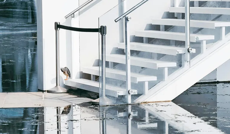 Wasser steht im Eingangsbereich eines Gebäudes, Treppenhaus spiegelt sich im Wasser; Hinweis auf Rückstau/Überflutung, Symbolfoto.